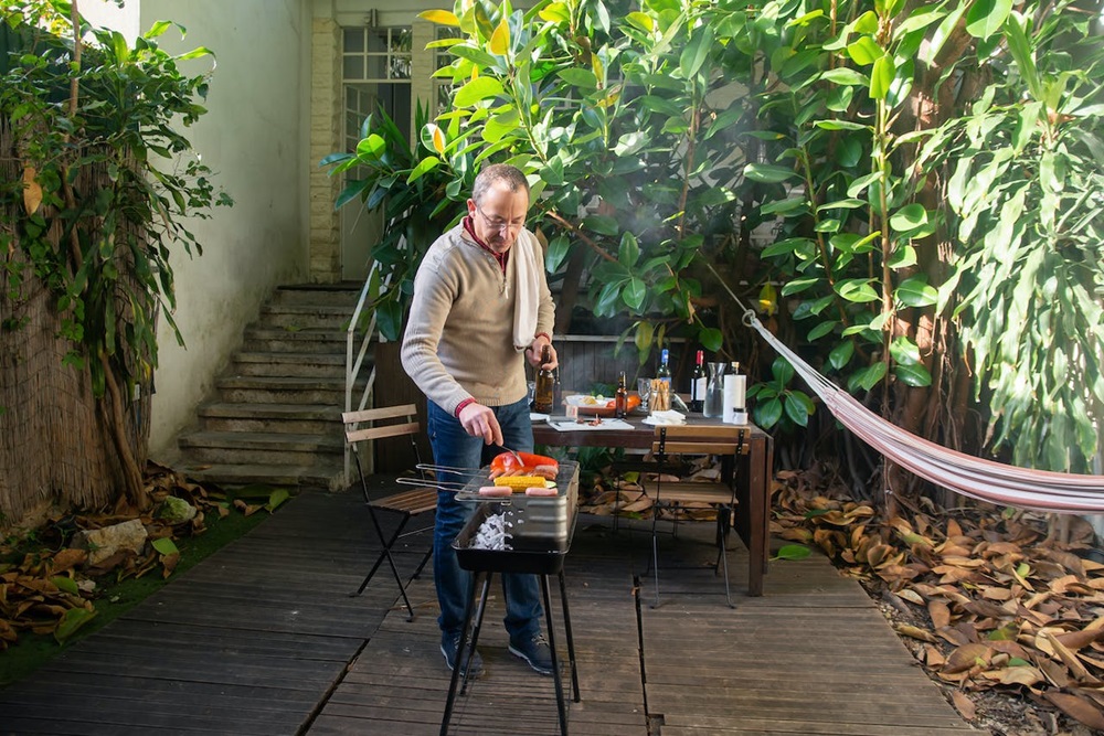 senior grilling food outside on a grill